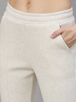 A person in 98degreenorth Women’s Beige Fleece Flared Sweatpants, one hand in pocket, shown waist to mid-thigh.