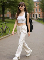 Woman in 98degreenorth Beige Fleece Flared Sweatpants walks outdoors; bike and buildings in background.