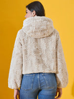 Woman in a 98degreenorth Beige Luxe Faux Fur Hooded Jacket, crop fit winter wear, facing away on yellow background.