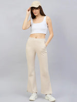 Woman in a white crop top, 98degreenorth Women’s Beige Multi Bootcut Sweatpants, sneakers, and cap, against a gray background.