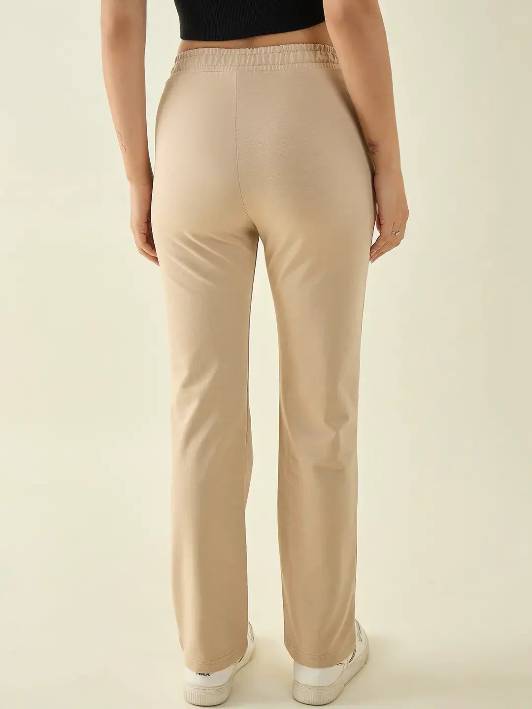 Woman in 98degreenorth beige straight fit cotton stretchable trousers and white sneakers, shown from the back.