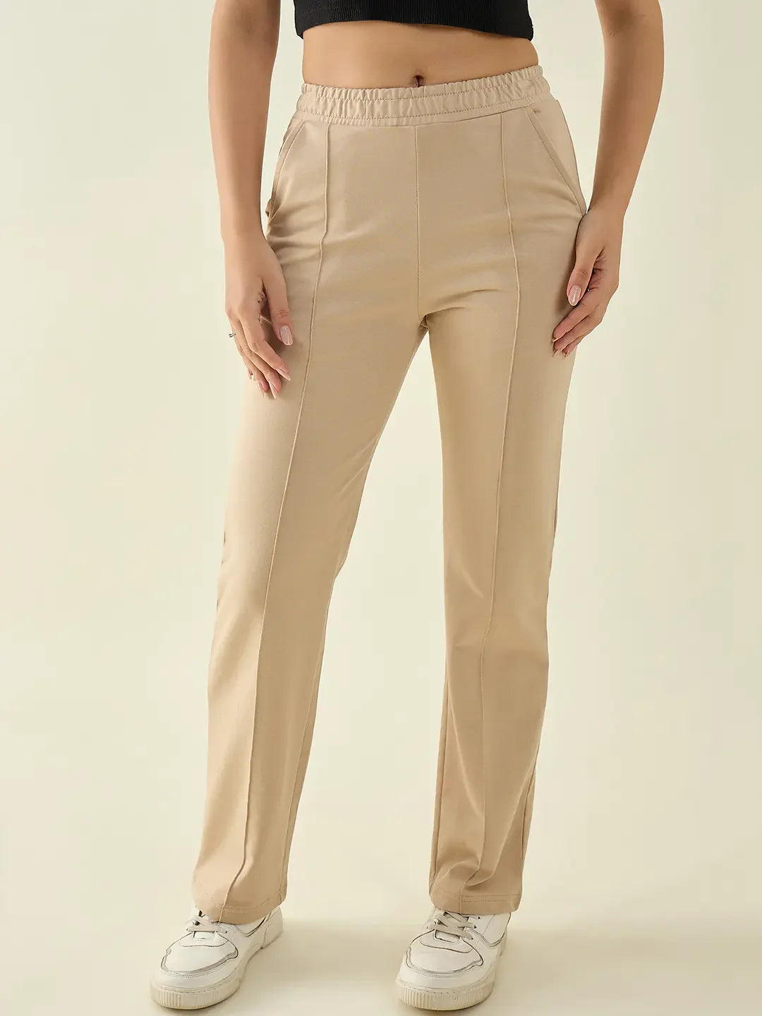 Woman wears 98degreenorth Women’s Beige Straight Fit Cotton Trousers with pockets, white sneakers, and a black crop top.