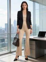 Woman in 98degreenorth Beige Stretch Fit Trousers stands by a desk in a modern office with a laptop and black handbag.