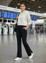 A woman wears 98degreenorth Women’s Black Bootcut Sweatpants with Side Slit in an airport terminal.