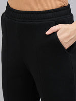 Model wears 98degreenorth Women’s Black Bootcut Sweatpants with Side Slit and a ribbed brown top, hand in pocket.
