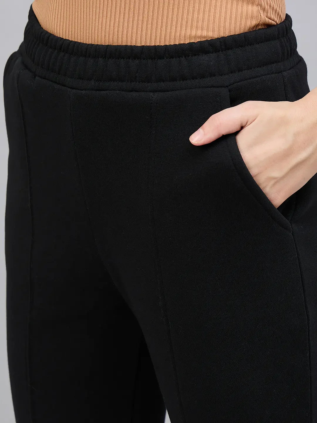 Model wears 98degreenorth Women’s Black Bootcut Sweatpants with Side Slit and a ribbed brown top, hand in pocket.