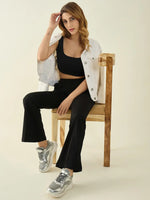 Woman sitting on a wooden chair, wearing 98degreenorth black flared bootcut cotton stretchable trousers and a crop top.