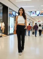 A woman in a white crop top and 98degreenorth Women’s Black Flared Bootcut Stretchable Trousers walks confidently.