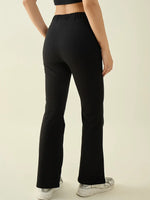 Person in 98degreenorth Women’s Black Flared Bootcut Cotton Stretchable Trousers, black crop top, and white sneakers, back view.