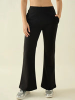 Model in 98degreenorth Women’s Black Flared Bootcut Cotton Trousers, hands in pockets, styled with silver sneakers.