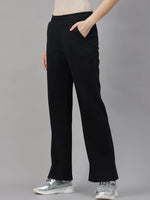 A person wears 98degreenorth Women’s Black Fleece Flared Sweatpants – Winter Casual Essential, hands in pockets.
