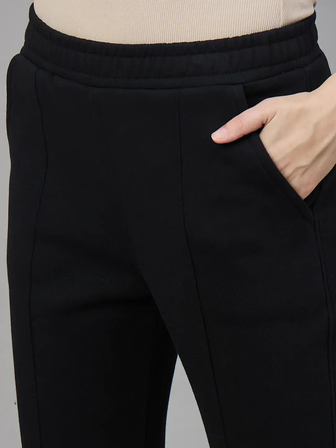 Model wears 98degreenorth Women’s Black Fleece Flared Sweatpants, hand in pocket, waist to mid-thigh view.