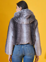 Woman faces away in 98degreenorth Women’s Black Premium Faux Fur Jacket with hood, against a yellow background.