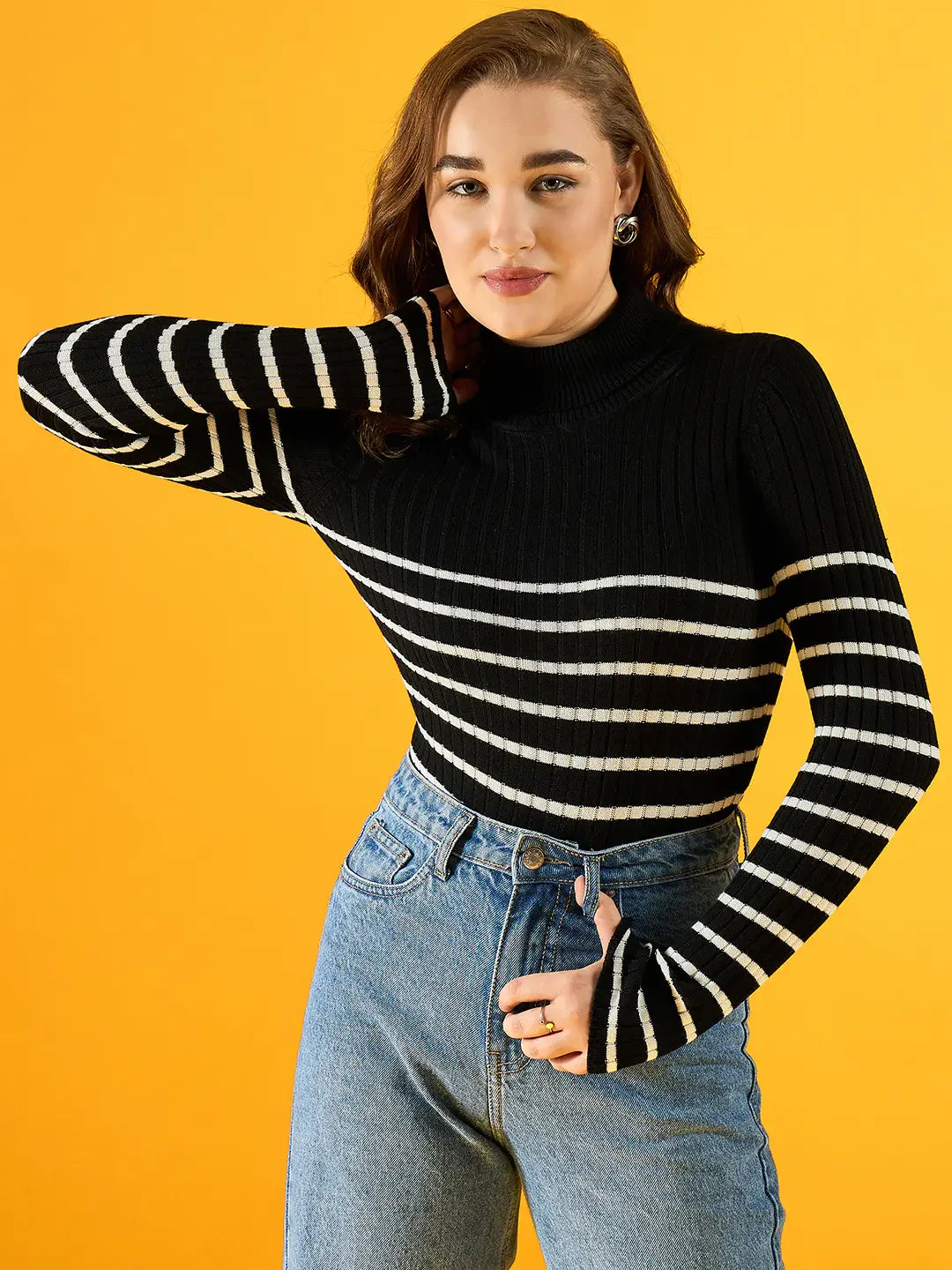 Woman in 98degreenorth’s black ribbed striped turtleneck sweater smiles against a vivid yellow background.