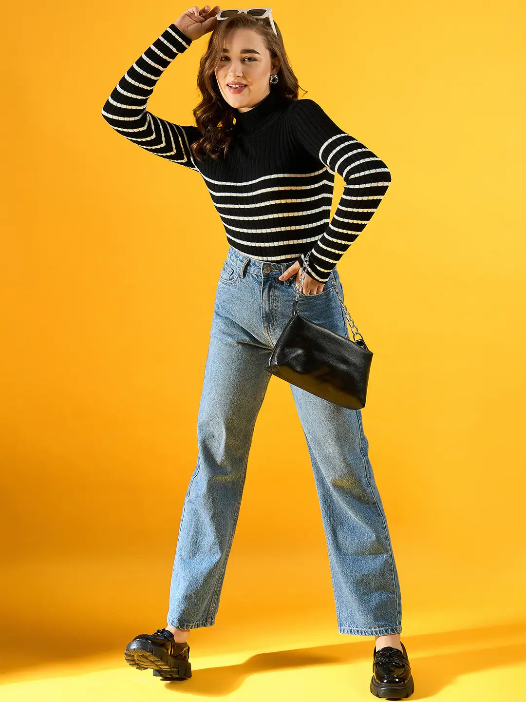 Woman in 98degreenorth Black Ribbed Striped Turtleneck Sweater with jeans and black shoes, holding a black handbag.