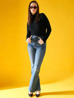 A woman models the 98degreenorth Women’s Black Ribbed Turtleneck Stretchable Sweater against a yellow background.