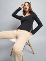 A modern Indian woman wears a 98degreenorth Women’s Black Square Neck Long Sleeve Top, paired with beige pants.