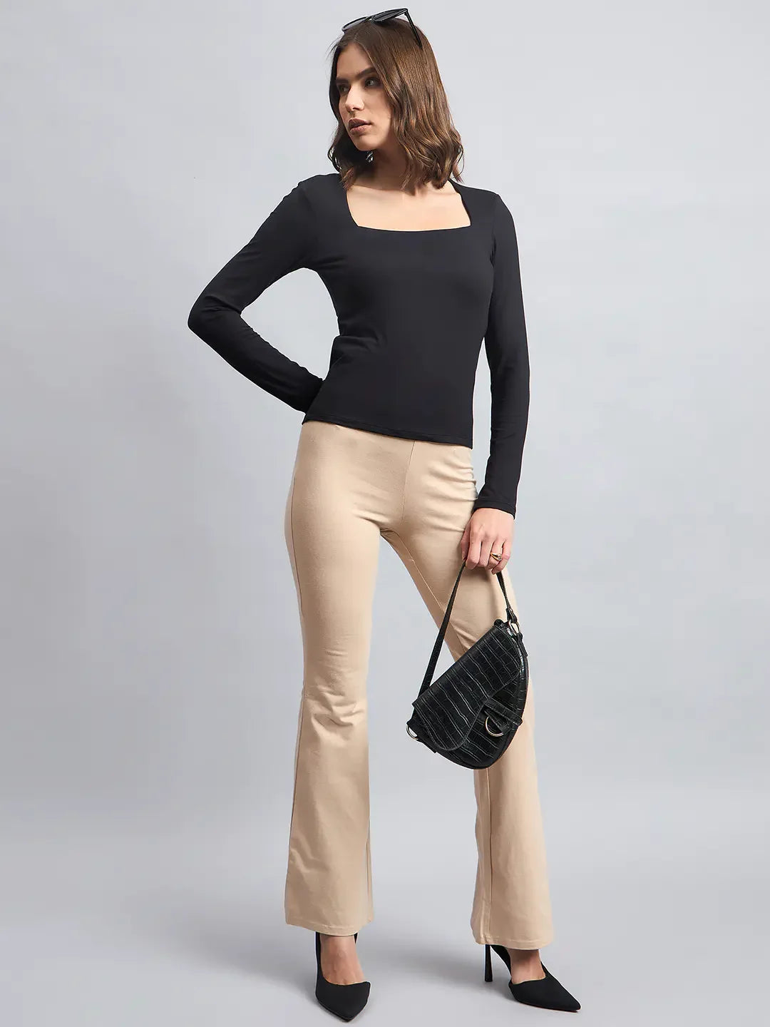 Woman in a 98degreenorth Women’s Black Square Neck Long Sleeve Top poses with beige pants, heels, sunglasses, and black purse.
