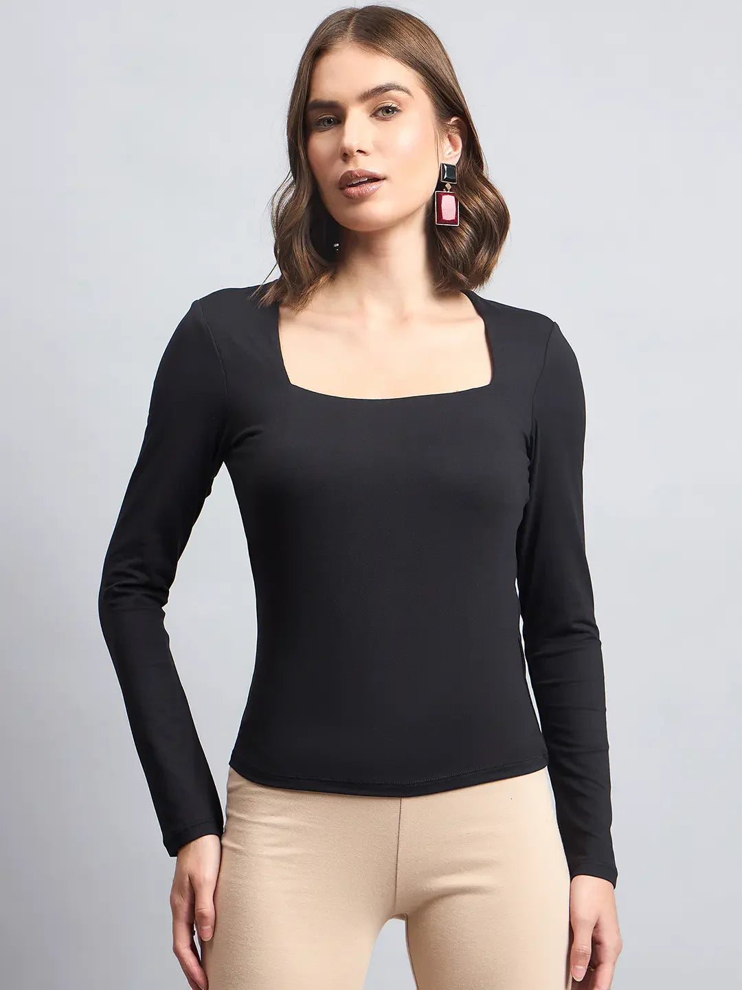 A modern Indian woman wears the 98degreenorth Women’s Black Square Neck Long Sleeve Top and pink geometric earrings.