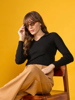 Woman in sunglasses on chair wears 98degreenorth Women’s Black Stretchable Ribbed Collar Sweater; yellow background.
