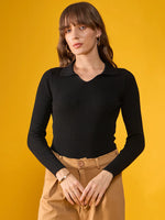 Woman in a 98degreenorth Black Stretchable Ribbed Collar Sweater and tan pants stands against a yellow background.