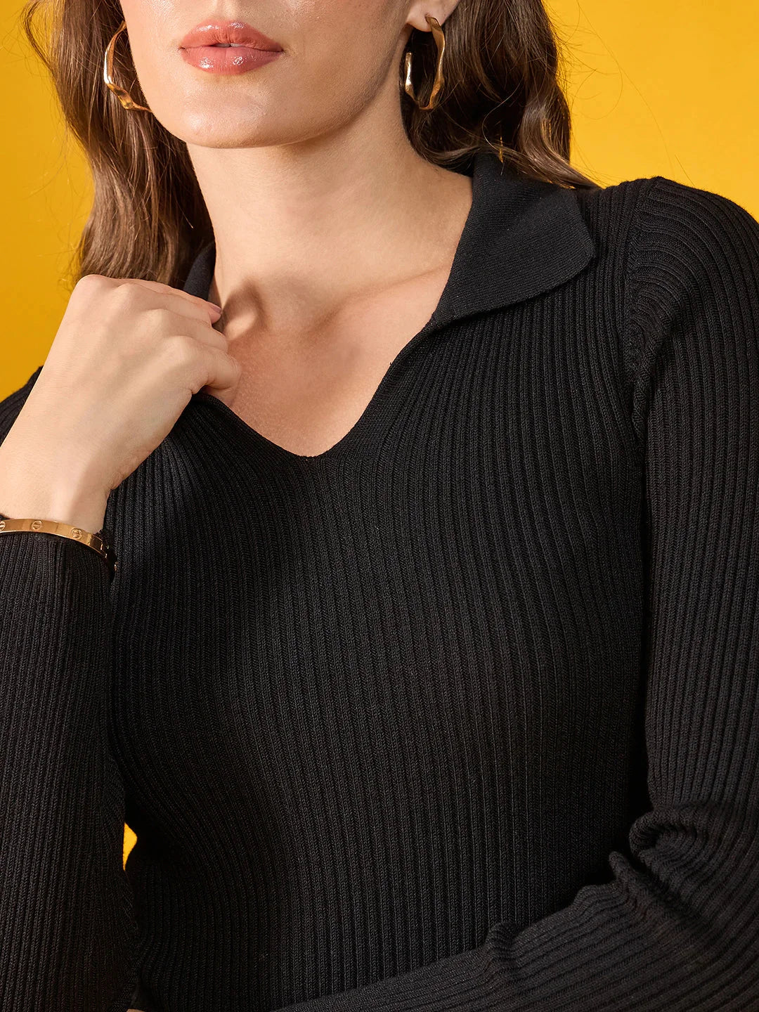 Woman in 98degreenorth Women’s Black Stretchable Ribbed Collar Sweater, gold jewelry, on a yellow background.