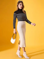Woman in 98degreenorth black striped ribbed high neck sweater, beige skirt, white boots & handbag on yellow background.
