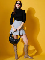 Woman wears 98degreenorth’s Black Turtle-Neck Ribbed Sweater with a gray skirt and black handbag against a yellow background.