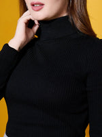A woman in a 98degreenorth Black Turtle-Neck Ribbed Sweater poses against a yellow background, touching her chin.