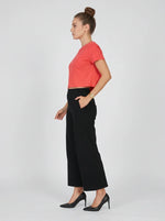 Woman in Women's Black Wide-Leg Cotton Pants by 98degreenorth stands in profile against a plain background.