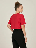 A woman with a bun models 98degreenorth's black high-rise wide-leg cotton pants against a plain background.