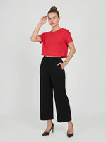 Woman wears 98degreenorth Black Wide-Leg High-Rise Cotton Pants, red crop top, and black heels, hand on head.
