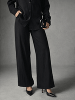 A person in 98degreenorth Women's Black Wide Leg Linen Pants stands against a gray background.