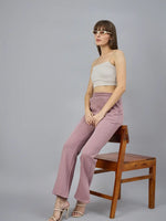 Woman wears 98degreenorth Blush Pink Bootcut Sweatpants, sitting sideways on a wooden chair against a gray background.