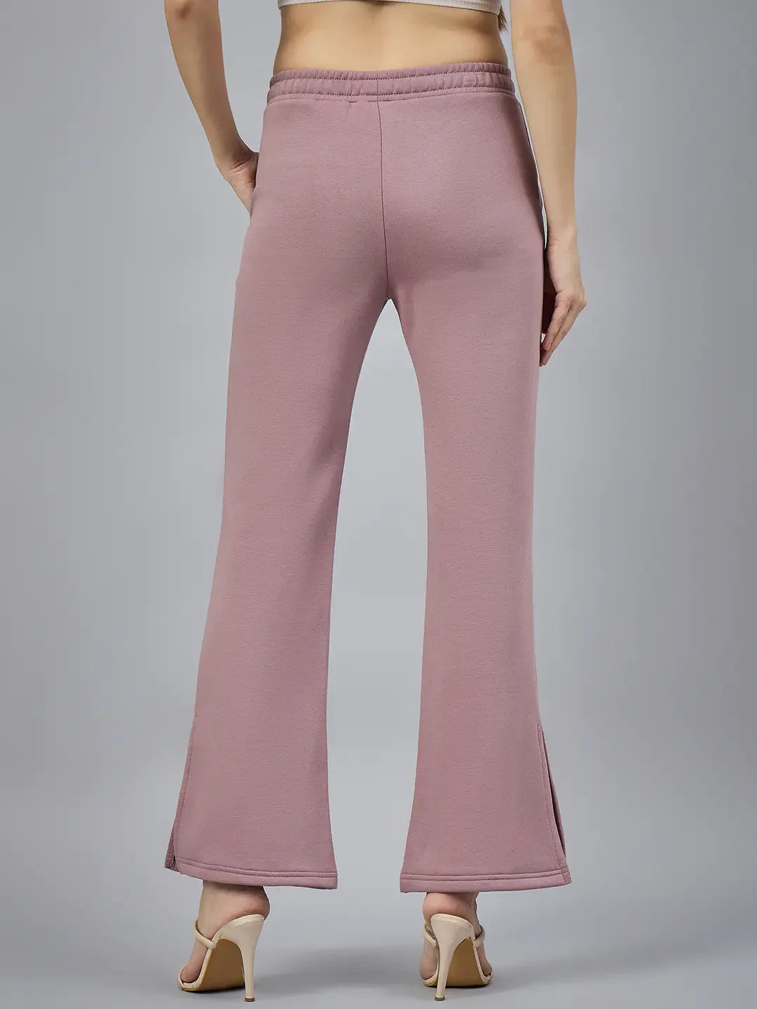 Model wears 98degreenorth Women’s Blush Pink Bootcut Sweatpants with beige heels, shown from the back on gray background.