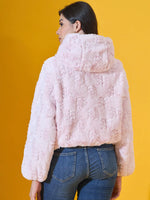 Woman in 98degreenorth’s blush pink faux fur jacket embraces chic winter style, standing against a yellow backdrop.