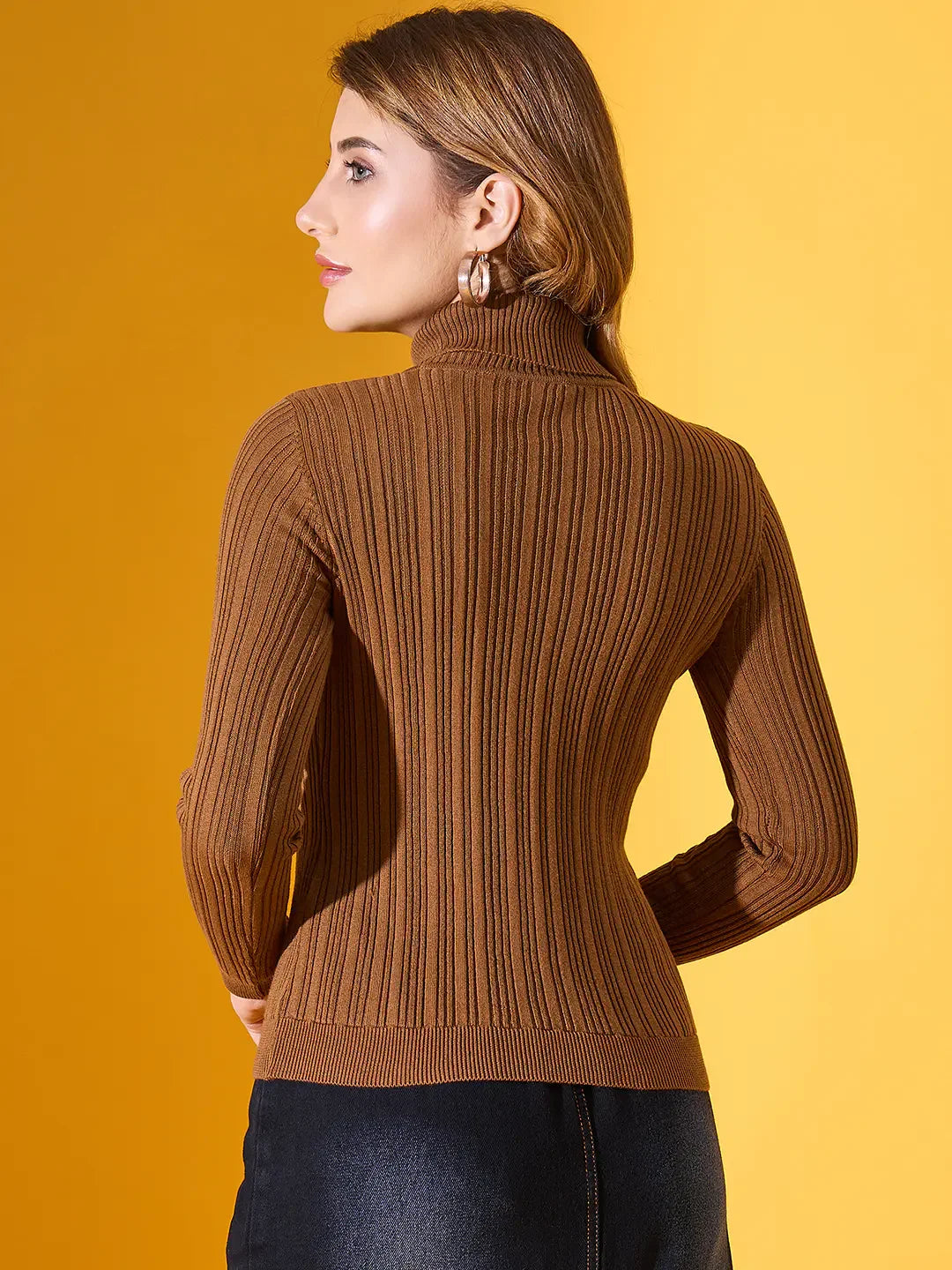 Woman wears 98degreenorth brown ribbed slim fit turtleneck sweater, facing away against yellow backdrop.