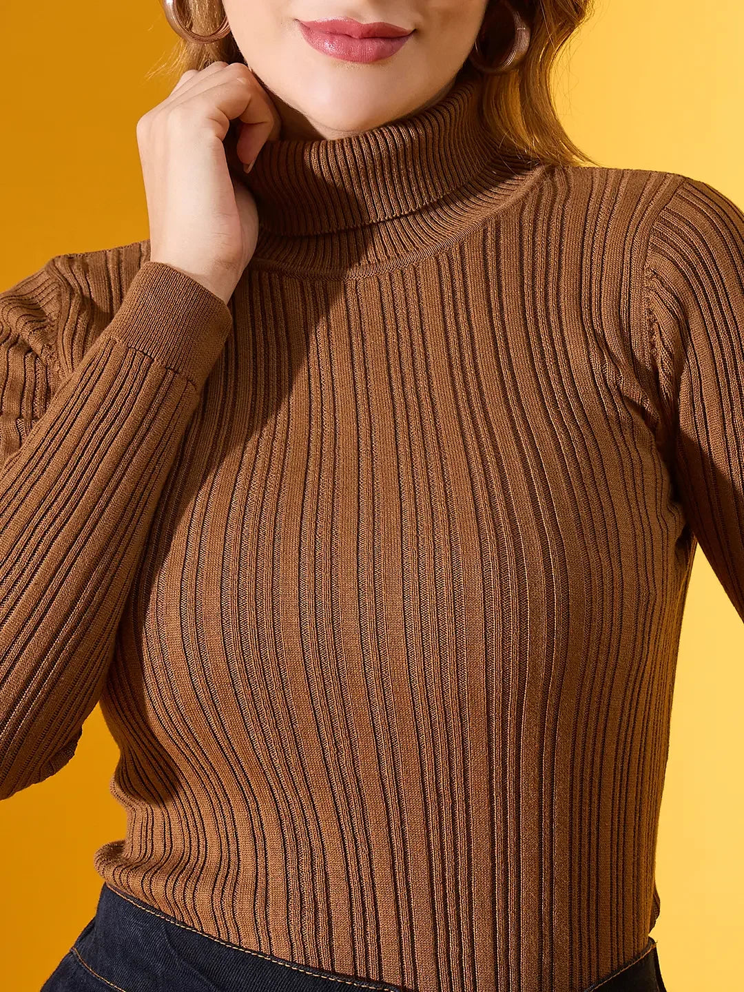 Woman wears 98degreenorth’s brown ribbed turtleneck slim fit pullover, a chic winter essential, against a yellow backdrop.