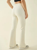 A person wears 98degreenorth Women’s Butter Flared Bootcut Cotton Stretchable Trousers, a black top, and white sneakers.