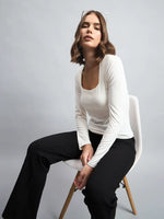A woman wears the 98degreenorth Women’s Butter Square Neck Long Sleeve Top with black pants against a plain gray background.
