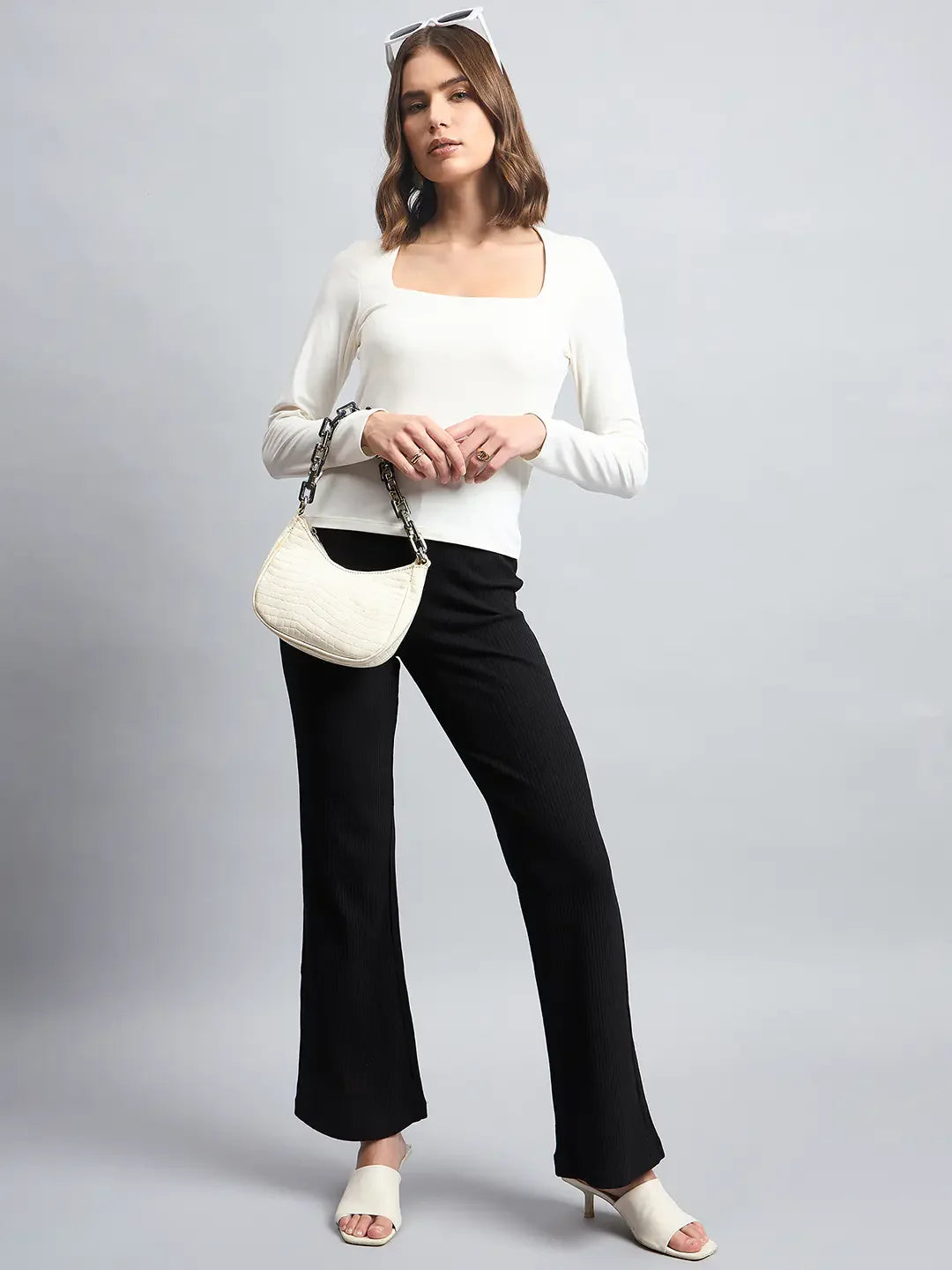 A woman in 98degreenorth’s Women’s Butter Square Neck Long Sleeve Top poses with heels and a small white handbag.