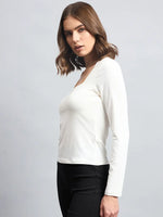 Woman in a 98degreenorth Women’s Butter Square Neck Long Sleeve Top and black pants against a gray background.