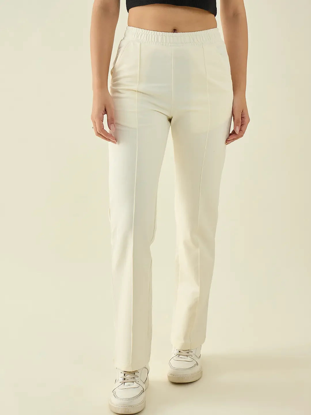 Woman wearing 98degreenorth’s Butter Straight Fit Cotton Stretchable Trousers with a black crop top and white sneakers.