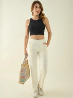 Woman in 98degreenorth Butter Straight Fit Cotton Stretchable Trousers, smiling and holding a colorful tote bag.