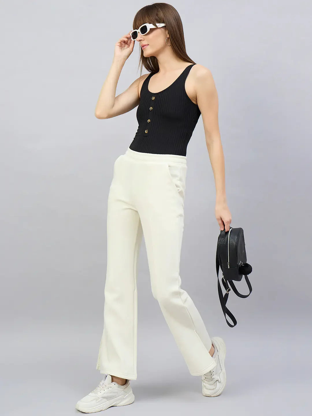 Woman in sunglasses and black top wears 98degreenorth Butter Yellow Flared Bootcut Sweatpants, holding a black backpack.