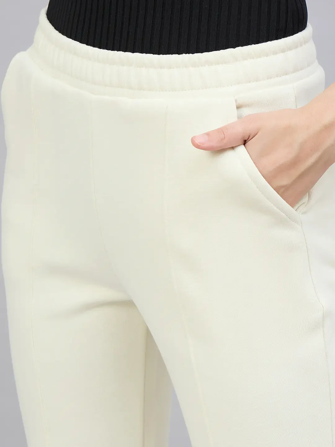 A person in 98degreenorth Women’s Butter Yellow Flared Bootcut Sweatpants, shown from the waist down with a hand in pocket.