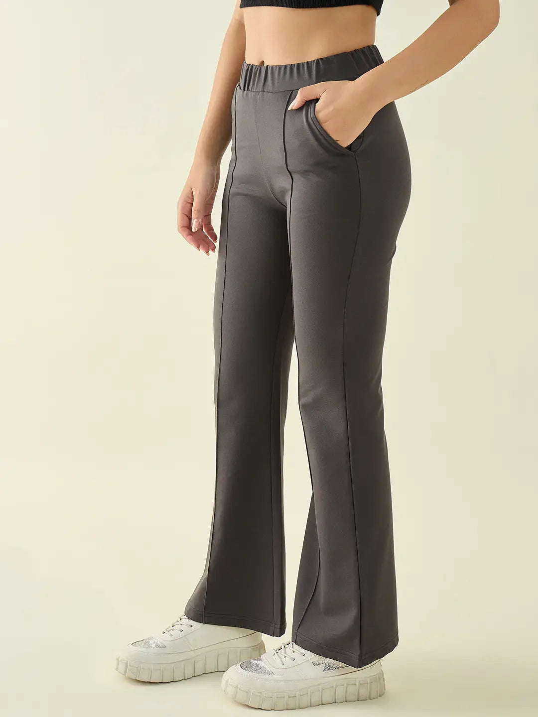 A woman in 98degreenorth Women’s Charcoal Flared Bootcut Cotton Stretchable Trousers stands with one hand in her pocket.