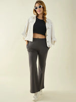 Woman in white jacket and sunglasses, black crop top, and 98degreenorth Charcoal Flared Fit Bootcut Trousers, smiling.