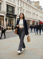 Woman in a blazer and 98degreenorth Women’s Charcoal Flared Fit Bootcut Trousers walks down a city street with a bag.