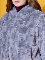 Woman in a 98degreenorth charcoal grey faux fur jacket over a maroon turtleneck, yellow background.